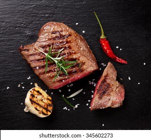 Grilled Beef Steak With Rosemary, Salt And Pepper On Black Stone Plate. Top View