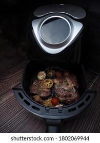 Grilled Beef Steak With Rosemary, Salt,tomatoes,mushrooms In Air-fryer Machine.Delicious Grilled Steaks With Vegetables Inside An Air Fryer Tray In Dark Tone.