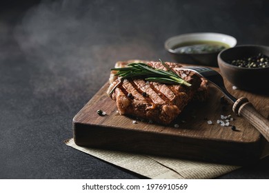 Grilled beef steak with with rosemary, spices and salt on cutting board. Selective focus, close up