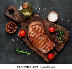 grilled beef steak with spices on a cutting board on a stone background
