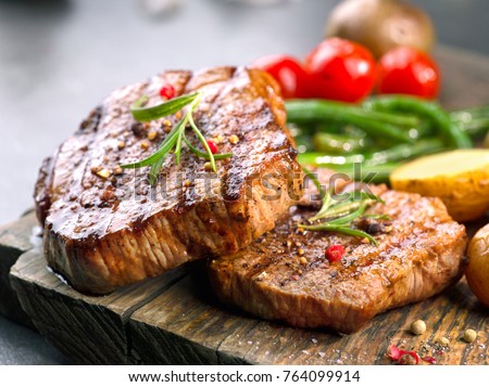 grilled beef steaks on wooden cutting board