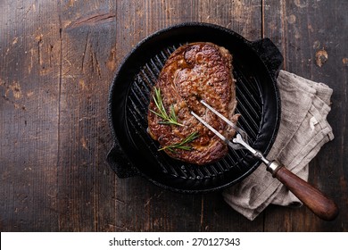 Grilled Black Angus Steak And Meat Fork On Grill Iron Pan On Wooden Background