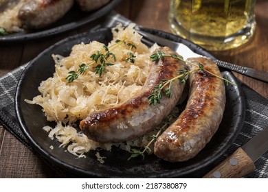 Grilled Bratwurst And Sauerkraut Garnished With Thyme On A Black Plate