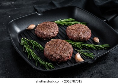 Grilled burger meat patties with spices on grill pan. Black background. Top view.