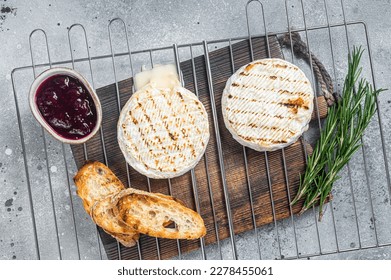 Grilled Camembert cheese on grill with cranberry sauce and toast. Gray background. Top view.