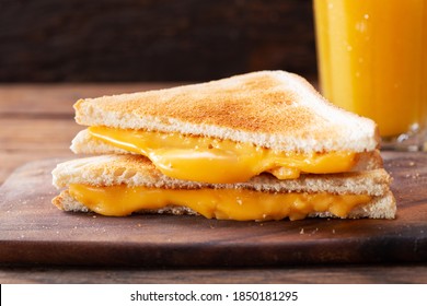 grilled cheese sandwiches with glass of orange juice on a wooden background - Powered by Shutterstock