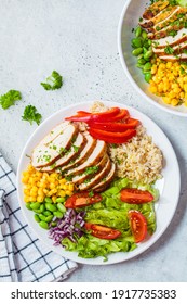 Grilled chicken breast with brown rice and vegetables in a white plate, gray background. Healthy food concept.
