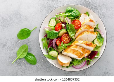Brust, Filet und frischer Gemüsesalat aus Salat, Arugula, Spinat, Gurken und Tomate gegrillt. Gesundes Mittagsmenü. Diät Essen. Draufsicht