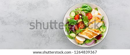 Grilled chicken breast, fillet and fresh vegetable salad of lettuce, arugula, spinach, cucumber and tomato. Healthy lunch menu. Diet food. Top view. Banner