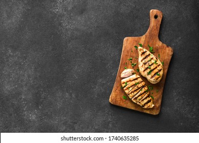 Grilled chicken breast, fillet, steak on wooden board, top view, copy space. Healthy keto, ketogenic meal, homemade bbq chicken meat ready to eat.
