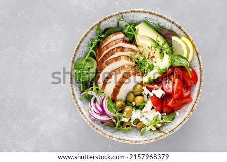 Grilled chicken breast and fresh vegetable salad with tomatoes, feta cheese, olives and avocado. Healthy food. Top view