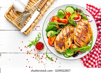 Grilled Chicken Breast. Fried Chicken Fillet And Fresh Vegetable Salad Of Tomatoes, Cucumbers And Arugula Leaves. Chicken Meat Salad. Healthy Food. Flat Lay. Top View. White Background