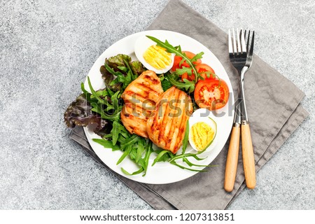 Grilled chicken breast. Fried chicken fillet and fresh vegetable salad of tomatoes, mangold and arugula leaves. Chicken meat salad. Healthy food. Flat lay. Top view. Gray background
