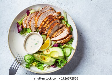 Grilled chicken breast salad with avocado, cucumber and mayonnaise dressing. Healthy food concept.