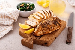 Grilled Chicken Breast With Spice Rub And Lemon On A Cutting Board, Sliced And Whole