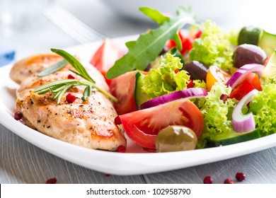 Grilled chicken breast with tomatoes, red pepper, organic green and kalamata olives, red onion, lettuce and fresh rocket and rosemary. Home made food. Concept for a tasty and healthy meal. Close up. - Powered by Shutterstock