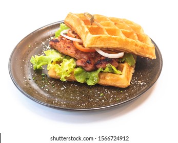 Grilled chicken breast waffle burger with fresh lettuces and sliced tomatoes and onion rings,scatter over with salt flake served in porcelain round dish with white background. Included cipping path.