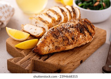 Grilled chicken breast whole and sliced on a cutting board with fresh lemon - Powered by Shutterstock