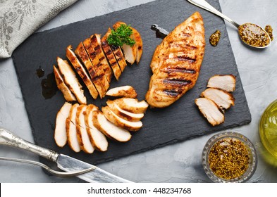 Grilled chicken fillets on slate plate. Gray concrete background - Shutterstock ID 448234768