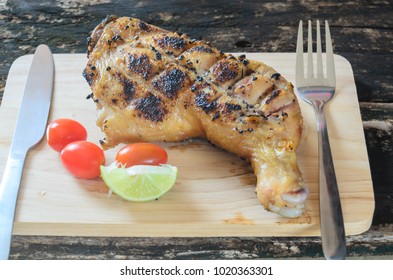Grilled chicken or Kai yang in Thai style. Plate on chopping board on wooden table.People are known and popular food eat with the papaya salad.Thai traditional food. Still life image/selective focus.