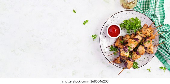 Grilled chicken kebab with red onions on a light table. Grilled meat skewers, shish kebab on light background. Top view, overhead, banner