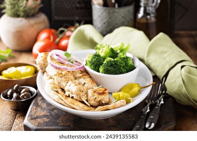 Grilled chicken kebabs on a pita with a side of stemed broccoli