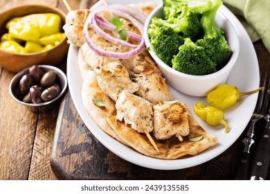 Grilled chicken kebabs on a pita with a side of stemed broccoli