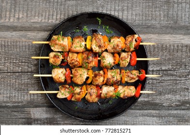 Grilled chicken kebabs with vegetables on wooden table, top view