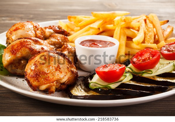 Grilled chicken legs with vegetables and red tomatoes. 
