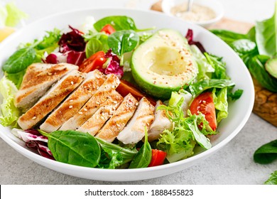 Gegrilltes Hühnerfleisch und frischer Gemüsesalat von Tomate, Avocado, Salat und Spinat. Gesundes und detoxes Lebensmittelkonzept. Ketogenische Diät. Buddha-Schüssel, weißer Hintergrund