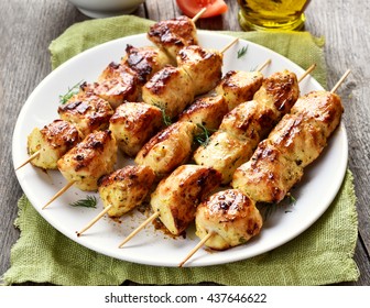 Grilled chicken on bamboo skewers on white plate