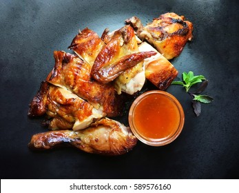 Grilled chicken on black dish served with sweet sauce.