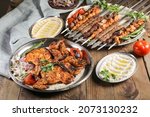 Grilled chicken on charcoal on bread and turkish and Arabic Traditional Mix Vali Kebab Plate inside Adana, Urfa, Chicken, Lamb, Liver and Beef, hummus, baba ganoush on bread on wooden background 