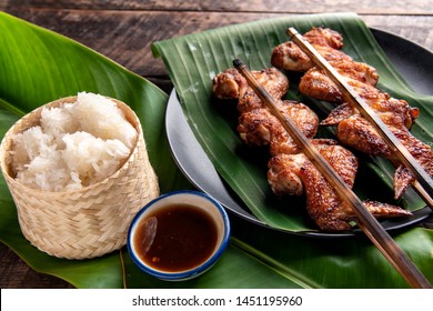 Grilled chicken Thailand style with sticky rice over banana leaf on wooden table background.
