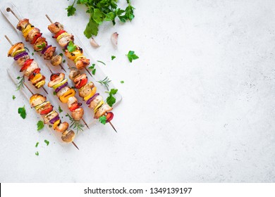 Grilled Chicken and Vegetable Skewers with  bell peppers, zucchini, onion and mushrooms on white background, top view, copy space. Meat and vegetables kebabs on skewers.