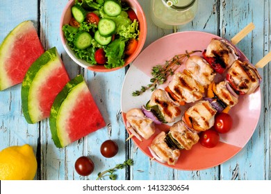 Grilled Chicken And Vegetable Skewers With Salad, Watermelon And Lemonade. Top View Table Scene Over A Blue Wood Background.