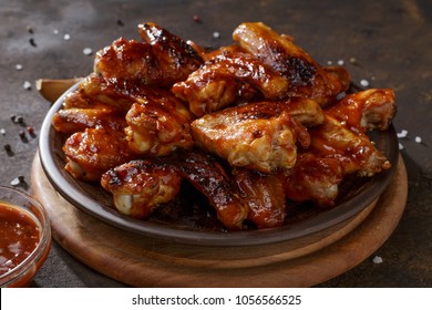 Grilled Chicken Wings With Bbq Sauce On The Clay Plate On The Brown Background.