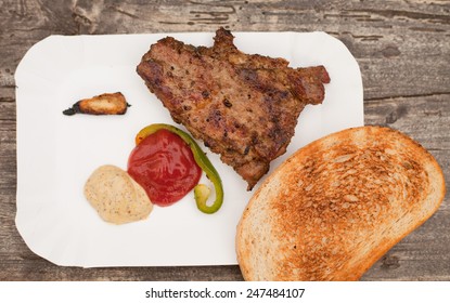 Grilled Chuck Steak On A White Plate With Grilled Roll And Sauces. Barbecue In A Garden. Pork, Beef Meat. Grilled Meat. Food, Restaurant, Menu. Nobody, Macro Perspective.