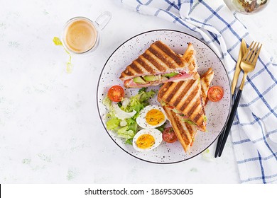 Grilled club sandwich panini with ham, tomato, cheese, avocado and cup of coffee. Delicious breakfast or snack. Top view, flat lay - Powered by Shutterstock