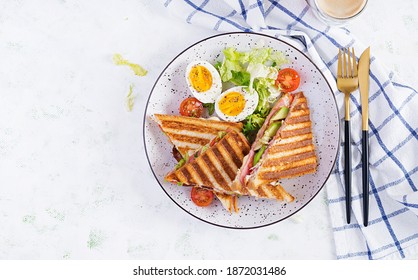 Grilled club sandwich panini with ham, tomato, cheese, avocado and cup of coffee. Delicious breakfast or snack. Top view, flat lay - Powered by Shutterstock