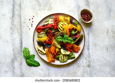 Grilled colorful vegetable : bell pepper, zucchini, eggplant on a plate over light grey slate, stone or concrete background. Top view with copy space. - Shutterstock ID 2080680802