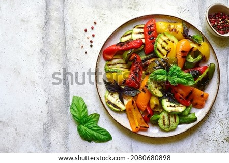 Grilled colorful vegetable : bell pepper, zucchini, eggplant on a plate over light grey slate, stone or concrete background. Top view with copy space.