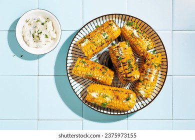 Grilled corn cobs with butter, cheese and herbs, Top view, copy space. Tiled background, hard light. - Powered by Shutterstock