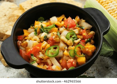 Grilled Corn Mango Tomato Salsa With Chips Served In A Black Salsa Bowl, Selective Focus