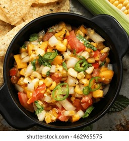 Grilled Corn Mango Tomato Salsa With Chips Served In A Black Salsa Bowl, Selective Focus