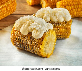 Grilled corn on cob with creamy topping and grated cotija cheese