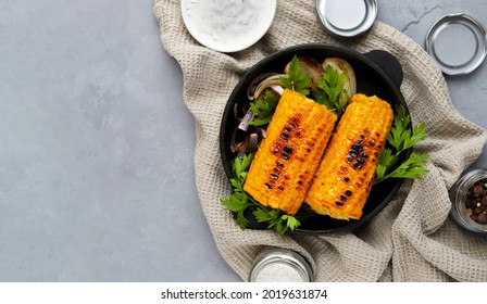 Grilled corn with spices, onions and parsley on a gray concrete background. Top view. Selective focus. Copy space. Banner - Powered by Shutterstock