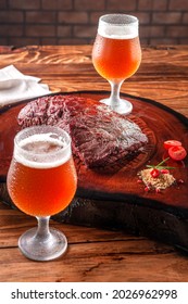 Grilled Denver Steak On Wooden Cutting Board With Two Sweaty Cold Tulipa Glasses Of Ale Draft Beer. Marble Meat Beef.