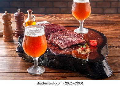 Grilled Denver Steak On Wooden Cutting Board With Two Sweaty Cold Tulipa Glasses Of Ale Draft Beer. Marble Meat Beef.