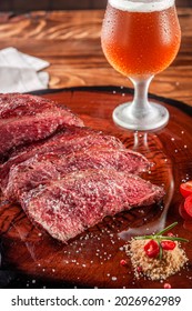 Grilled Denver Steak Sliced On Wooden Cutting Board With Parrilla Salt And Sweaty Glass Of Beer. Marble Meat Beef - Closeup.